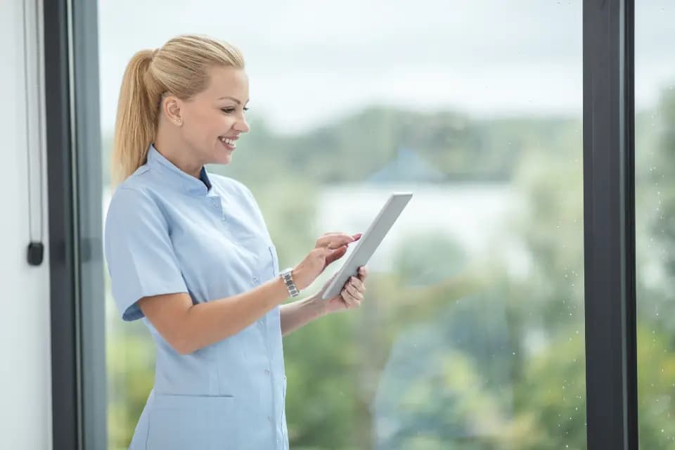 A smiling nurse checking a tablet